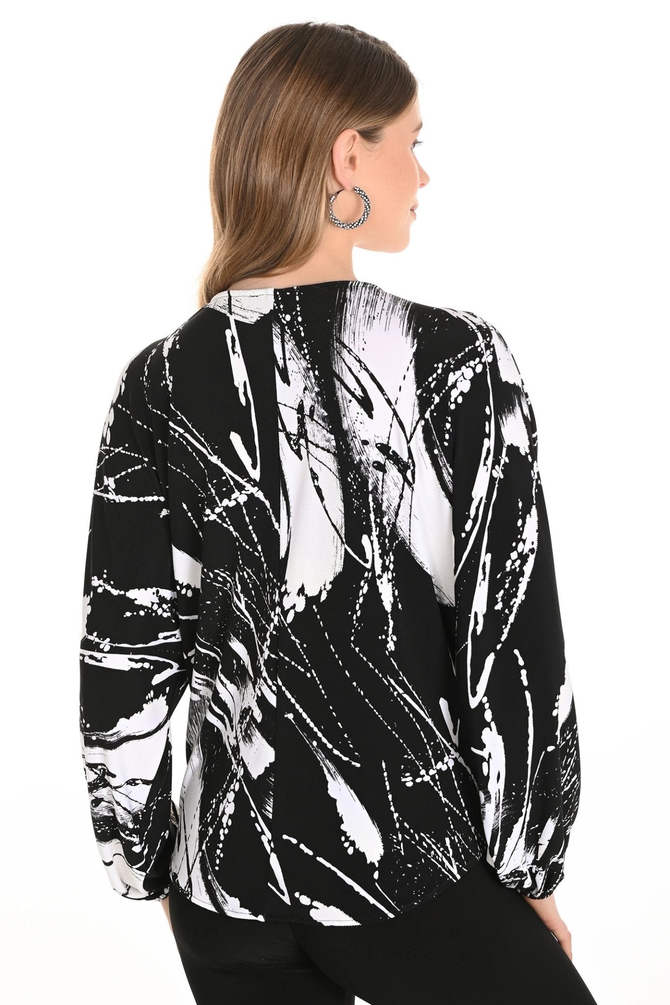 Woman wearing a black and white abstract patterned top on a white background