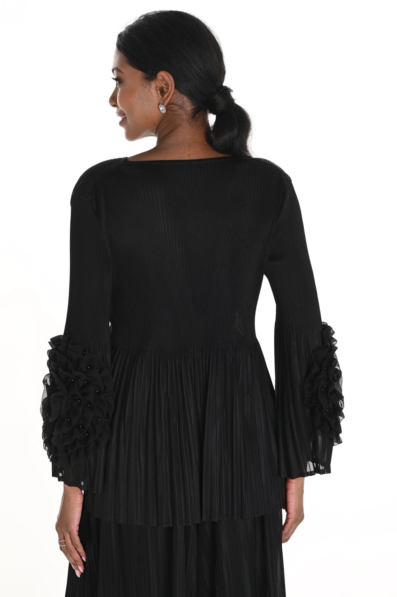 Woman wearing a black dress with ruffled sleeves on a white background