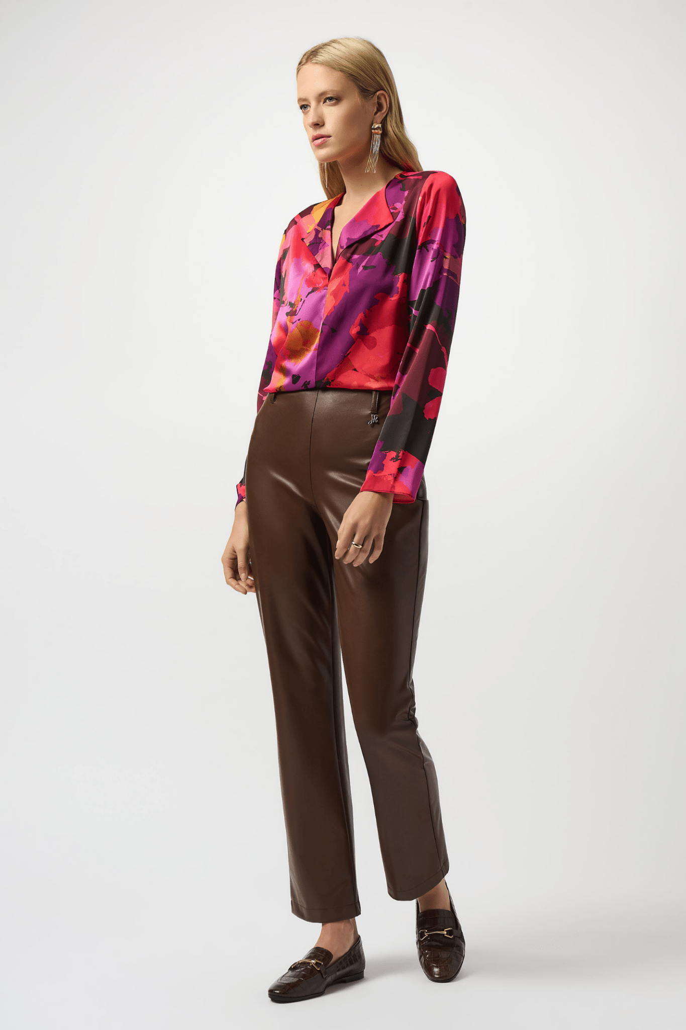 Woman wearing a colorful blouse and brown pants on a white background