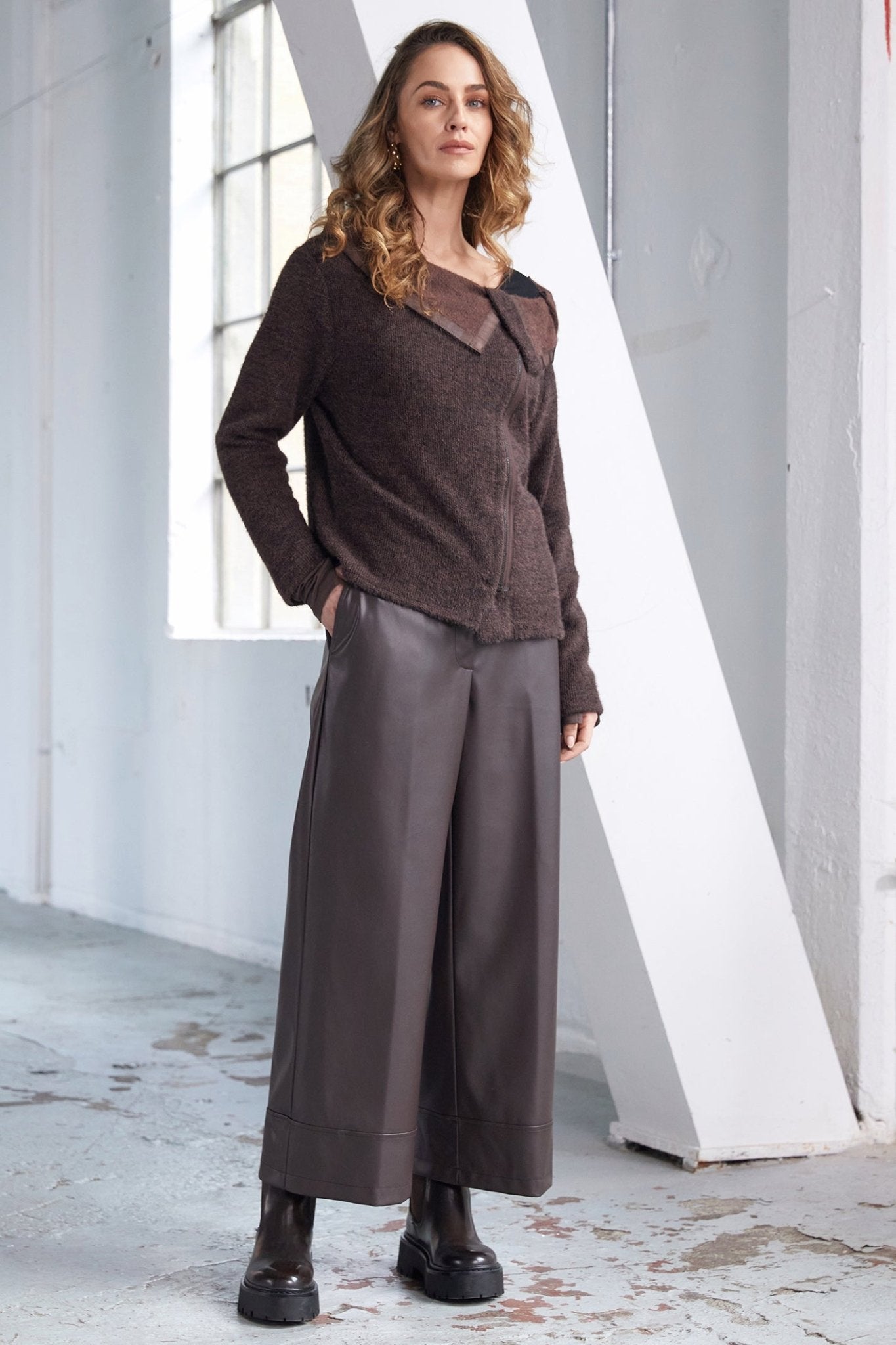 Woman wearing a brown outfit standing in a minimalistic indoor setting.