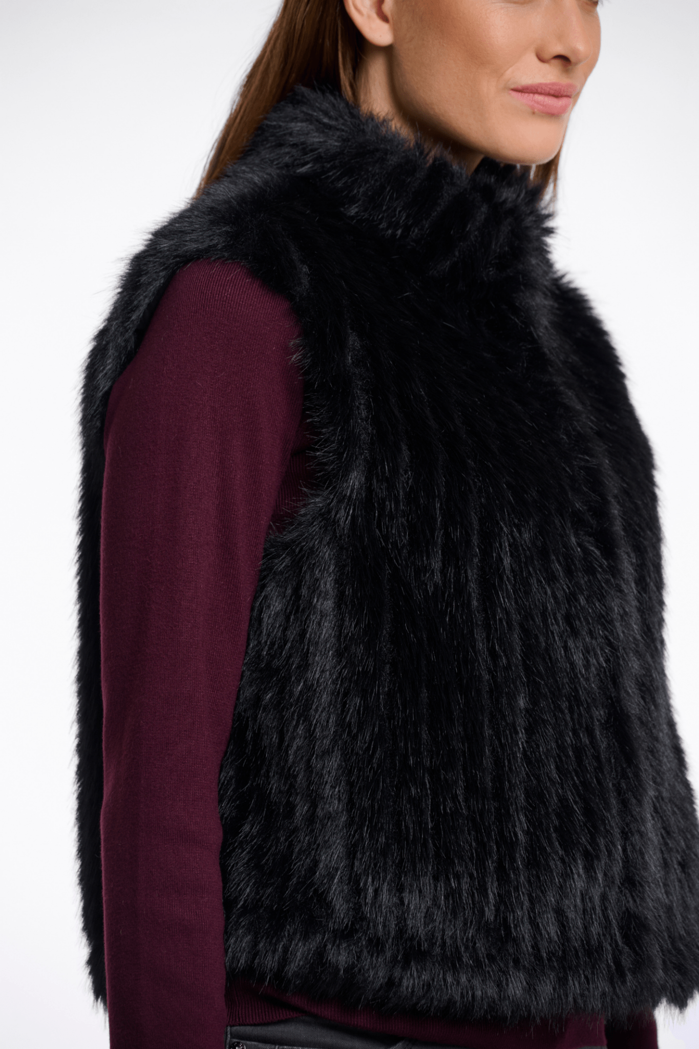 Person wearing a black fur vest on a white background