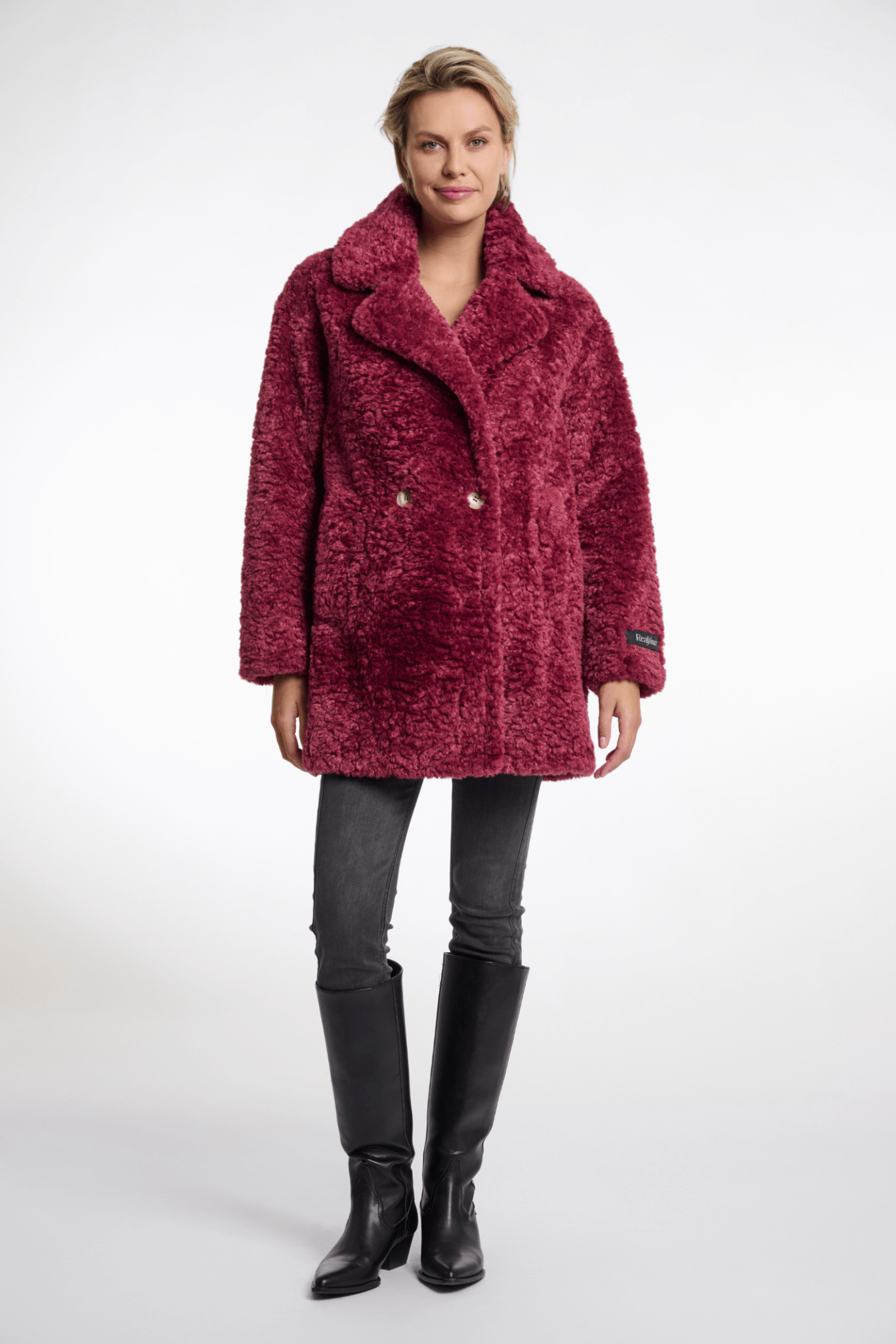 Woman wearing a red textured coat on a white background