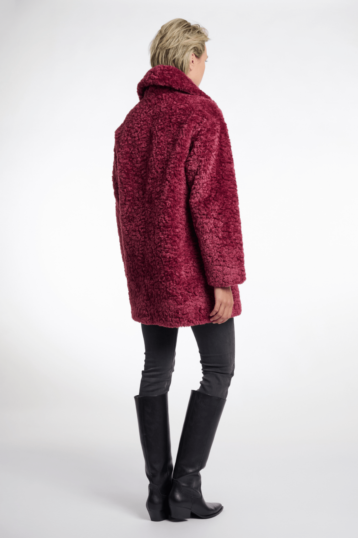 Person wearing a red coat and black boots on a white background