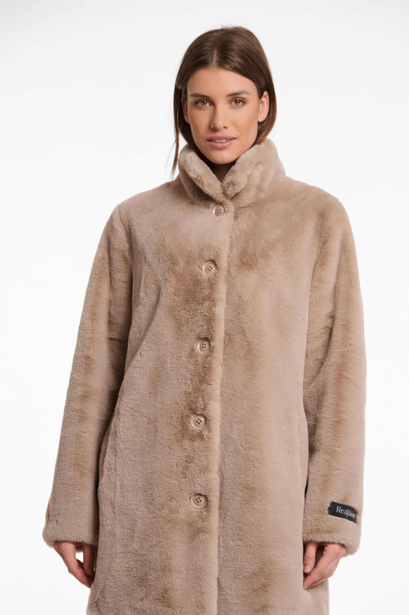 Woman wearing a beige coat with a fur-lined hood on a white background