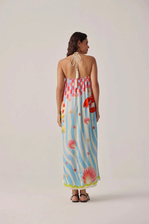 Back view of a model wearing Noib Riva Coverup – Summer Zest with ocean-inspired print and halter neck tie by Noib. Shop Noib at Dotique.