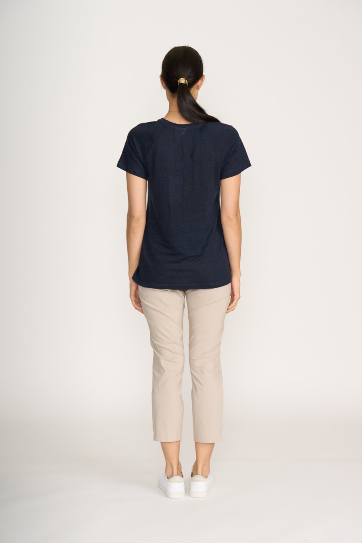 Woman wearing Foil Fo8269 Finish Line Pant Sand viewed from behind with navy top, shop Foil at Dotique