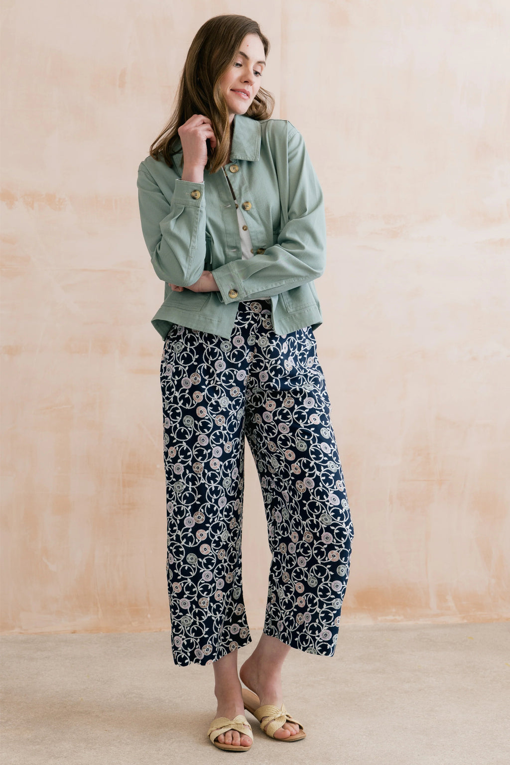 Model wearing Lily & Me LM26023 Greta Trousers Sea Holly Navy with floral print paired with a light green jacket by Lily & me. Shop Lily & me at Dotique.