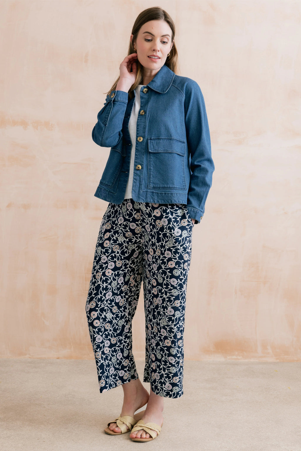 Woman wearing Lily & Me LM26023 Greta Trousers Sea Holly Navy with floral design paired with a blue button-up jacket by Lily & me. Shop Lily & me at Dotique.