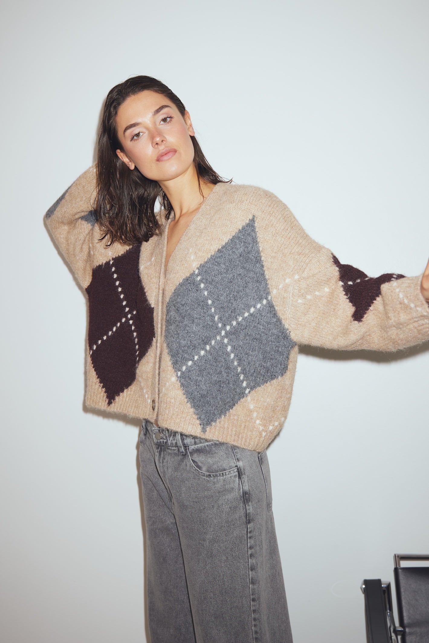 Woman wearing a patterned sweater and jeans against a plain background