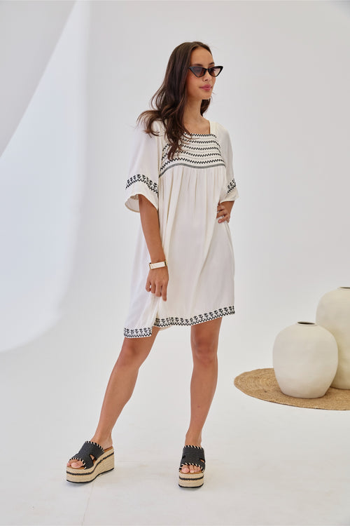 Woman wearing NKN Nekane Jelani White Short Viscose Dress with 3/4 Sleeves and Bicolour Embroidery by nkn nekane, shop at Dotique