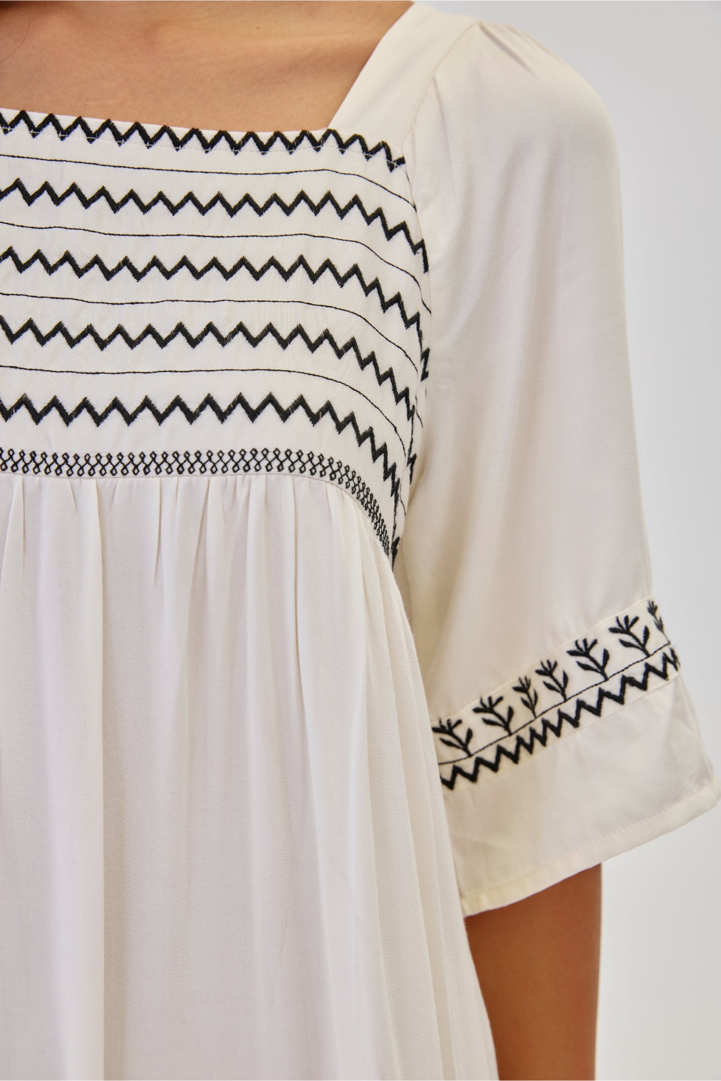 Close-up of black embroidery on NKN Nekane Jelani White Short Viscose Dress with 3/4 Sleeves and Bicolour Embroidery, shop nkn nekane at Dotique