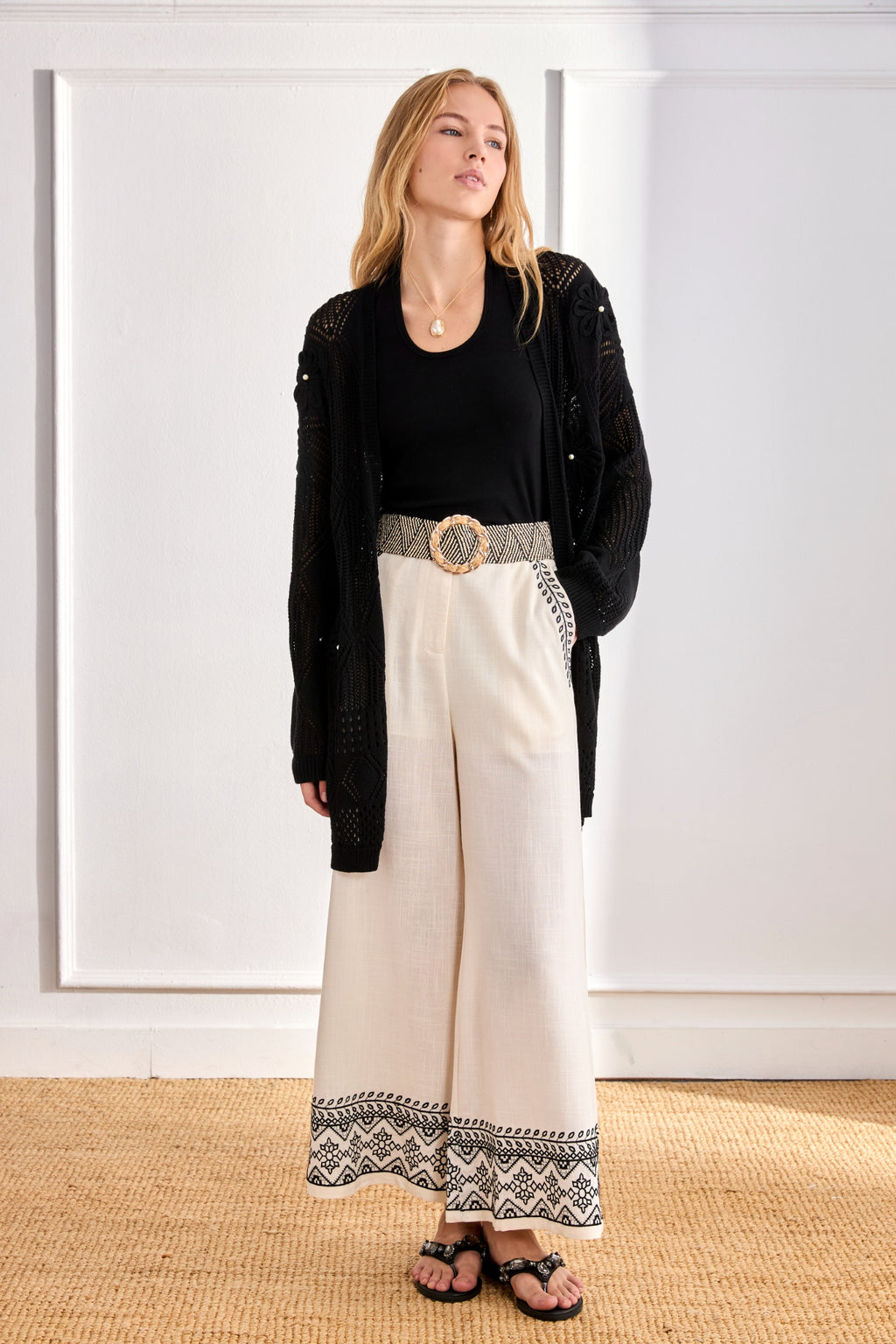 Model dressed in black top and cardigan wearing NKN Nekane Arsi Ivory Linen Trousers with Embroidery on Hem and Pocket by nkn nekane, shop Dotique