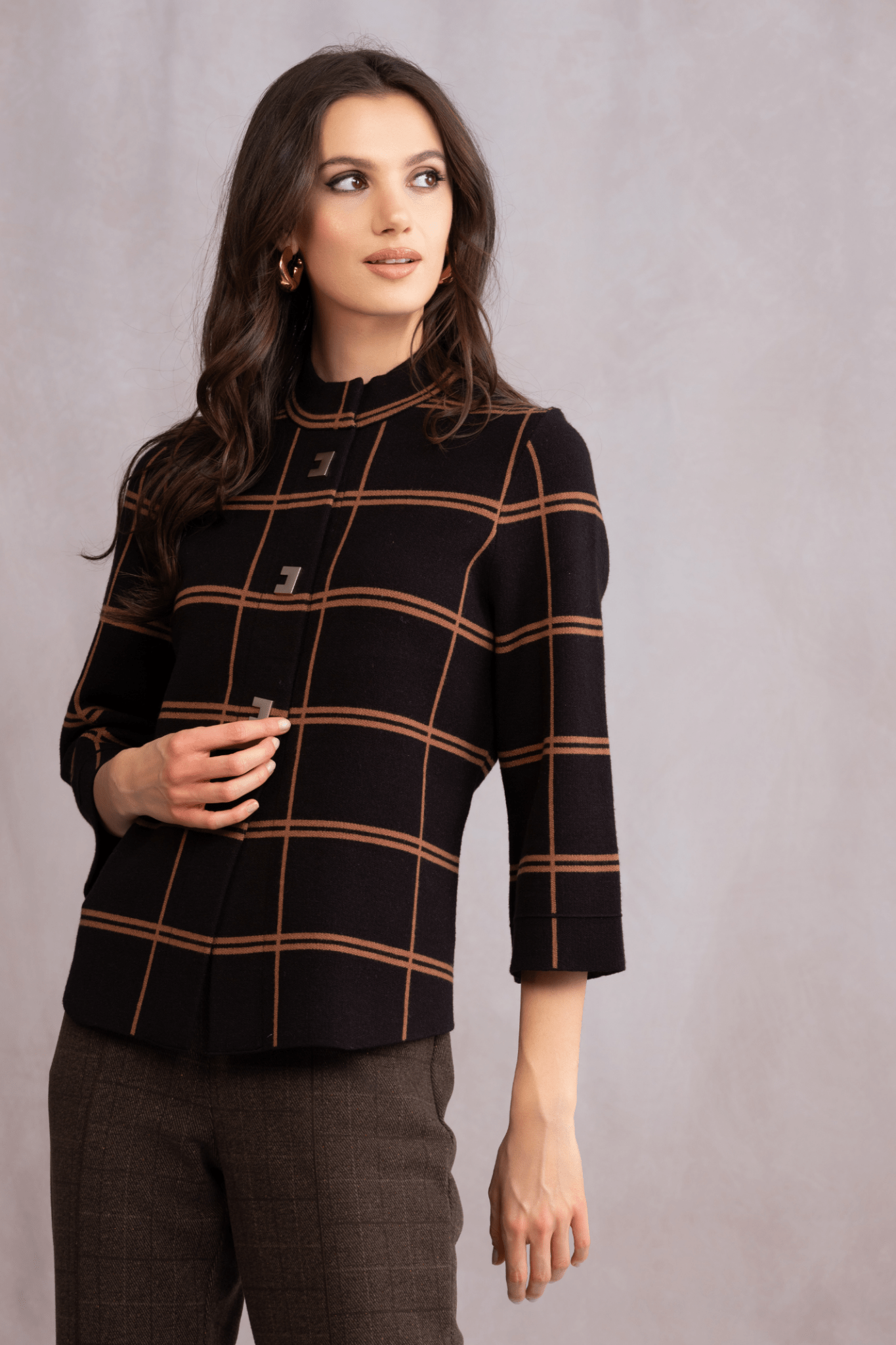 Woman wearing a black checkered top with brown lines on a gray background
