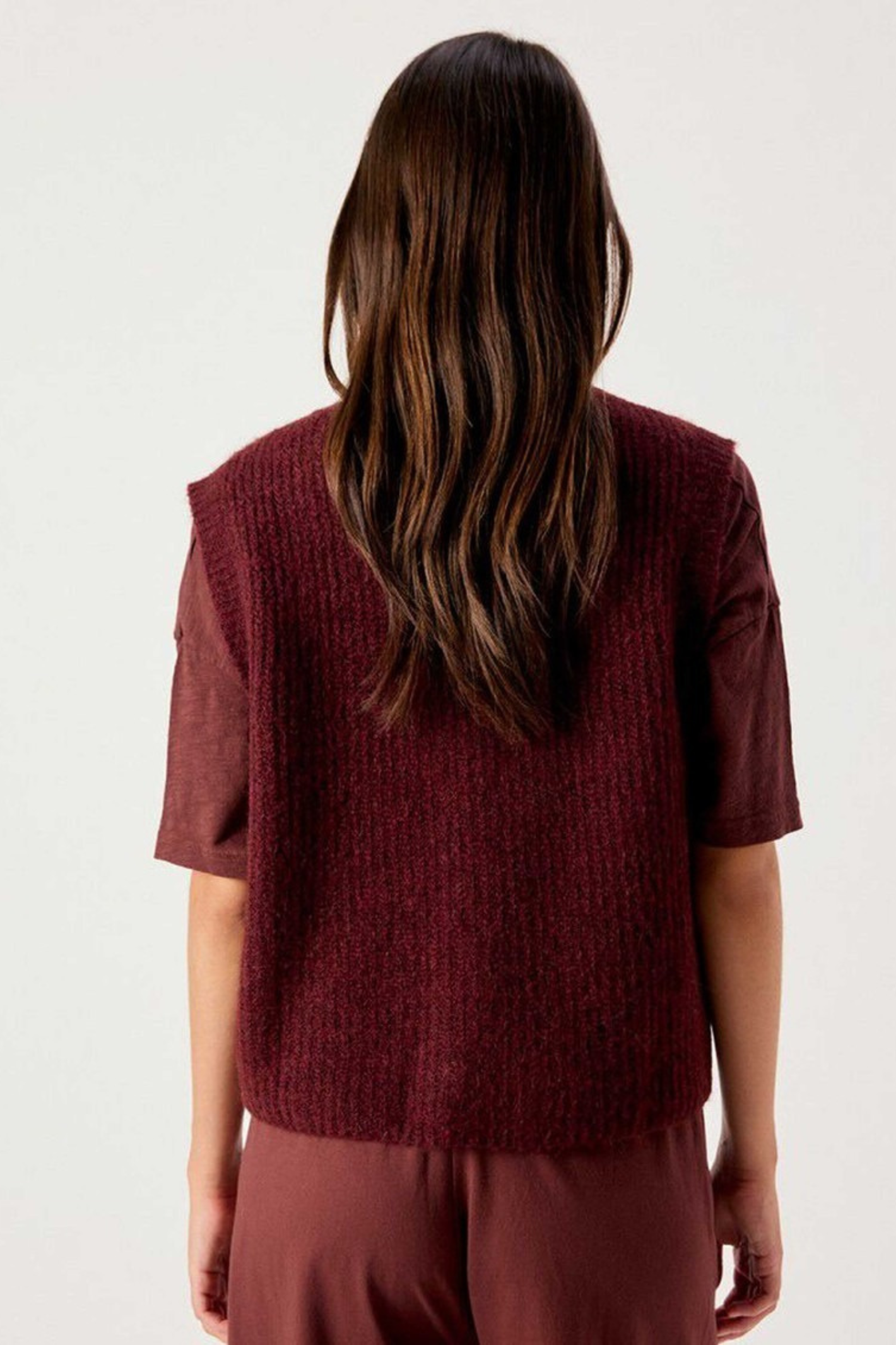 Shop the American Vintage East Knitted Waistcoat in Acerola Chine at Dotique. A soft alpaca blend knitted waistcoat with a relaxed fit, button front and rich burgundy melange colour.