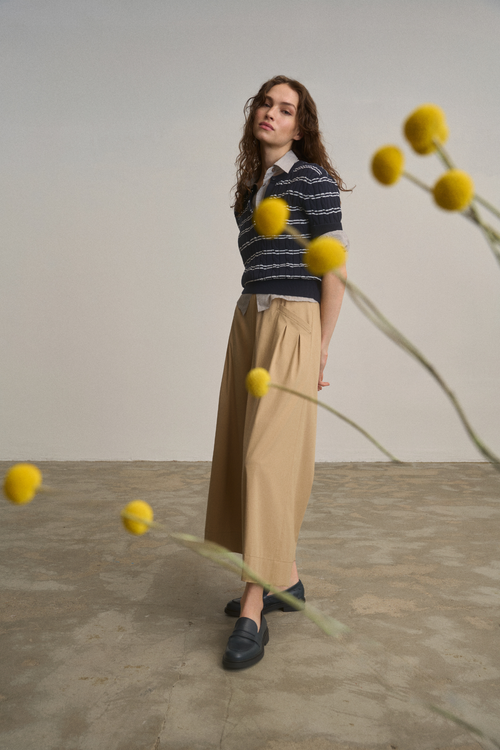 Model wearing Anna Montana 6604 212 Meret Culottes Flexi New Port Desert Sand in a soft beige tone paired with a navy striped top, shop Anna Montana at Dotique.