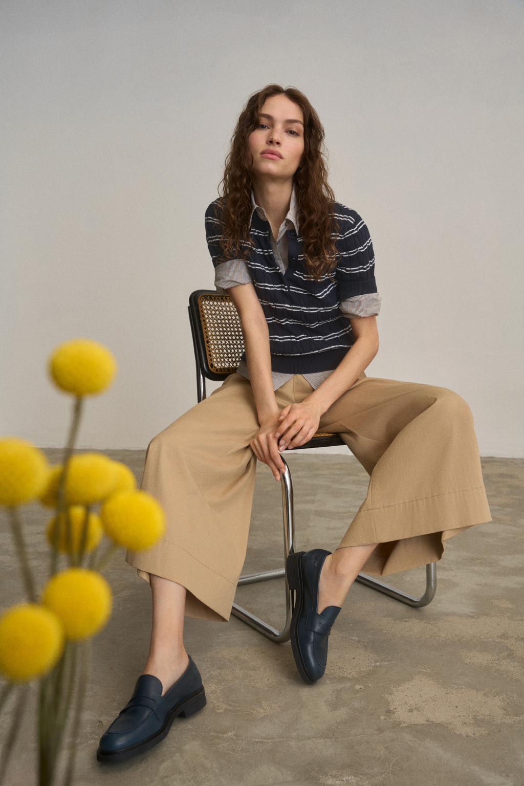 Model seated wearing Anna Montana 6604 212 Meret Culottes Flexi New Port Desert Sand in wide-leg beige paired with a navy striped top, shop Anna Montana at Dotique.