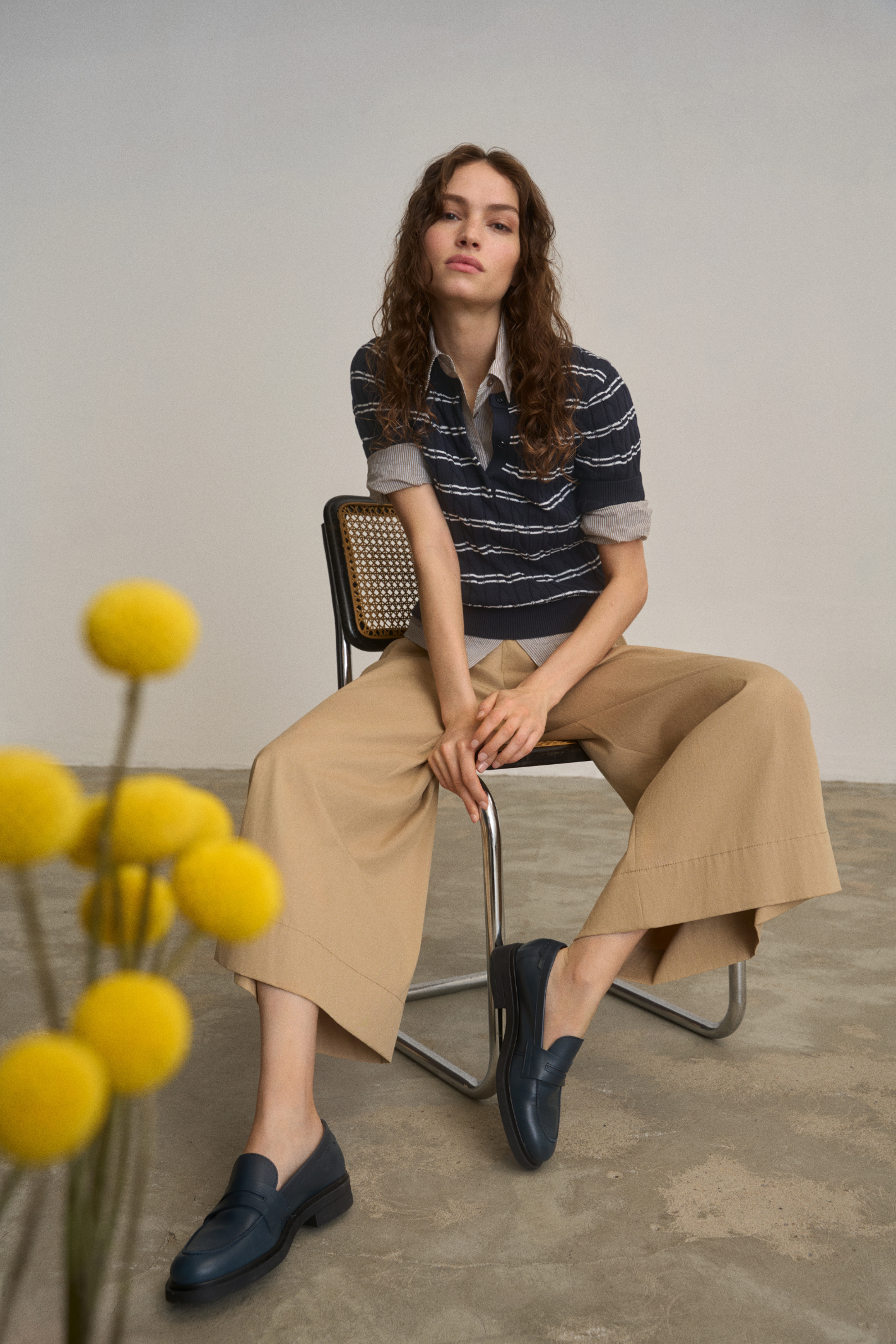 Model seated wearing Anna Montana 6604 212 Meret Culottes Flexi New Port Desert Sand in wide-leg beige paired with a navy striped top, shop Anna Montana at Dotique.