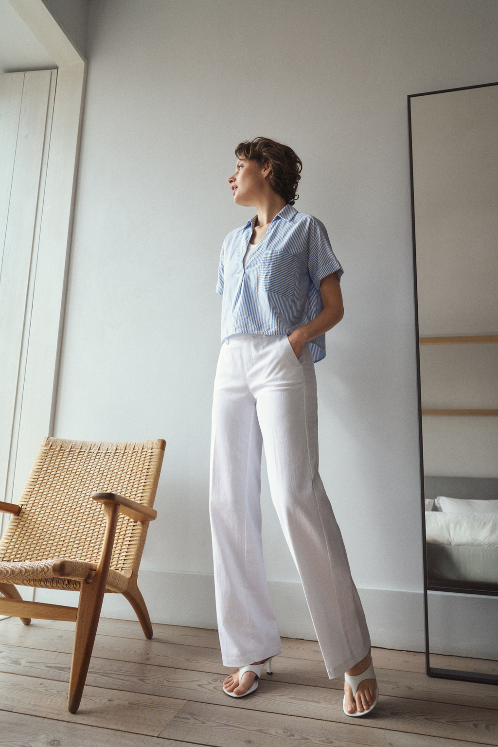 Model wearing Anna Montana 1045 Mila Wide Flexi Milano Jeans Weiss in crisp white wide-leg style paired with a light blue striped short-sleeve shirt, shop Anna Montana at Dotique.