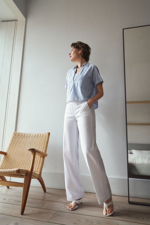 Model wearing Anna Montana 1045 Mila Wide Flexi Milano Jeans Weiss in crisp white wide-leg style paired with a light blue striped short-sleeve shirt, shop Anna Montana at Dotique.