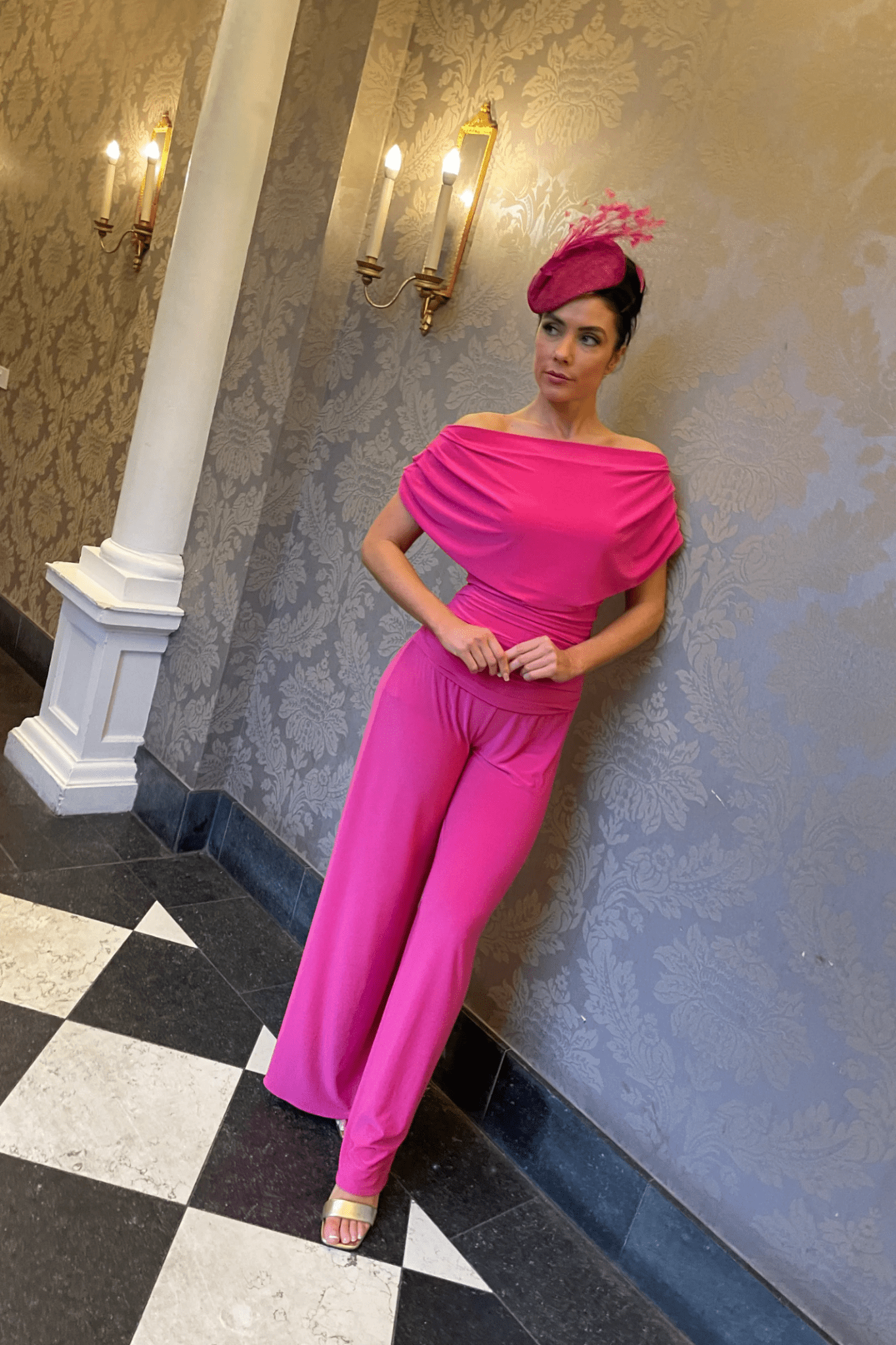 Woman wearing a bright pink ATOM LABEL Carbon Jumpsuit in Hot Pink, styled with a matching hat, shop ATOM LABEL at Dotique