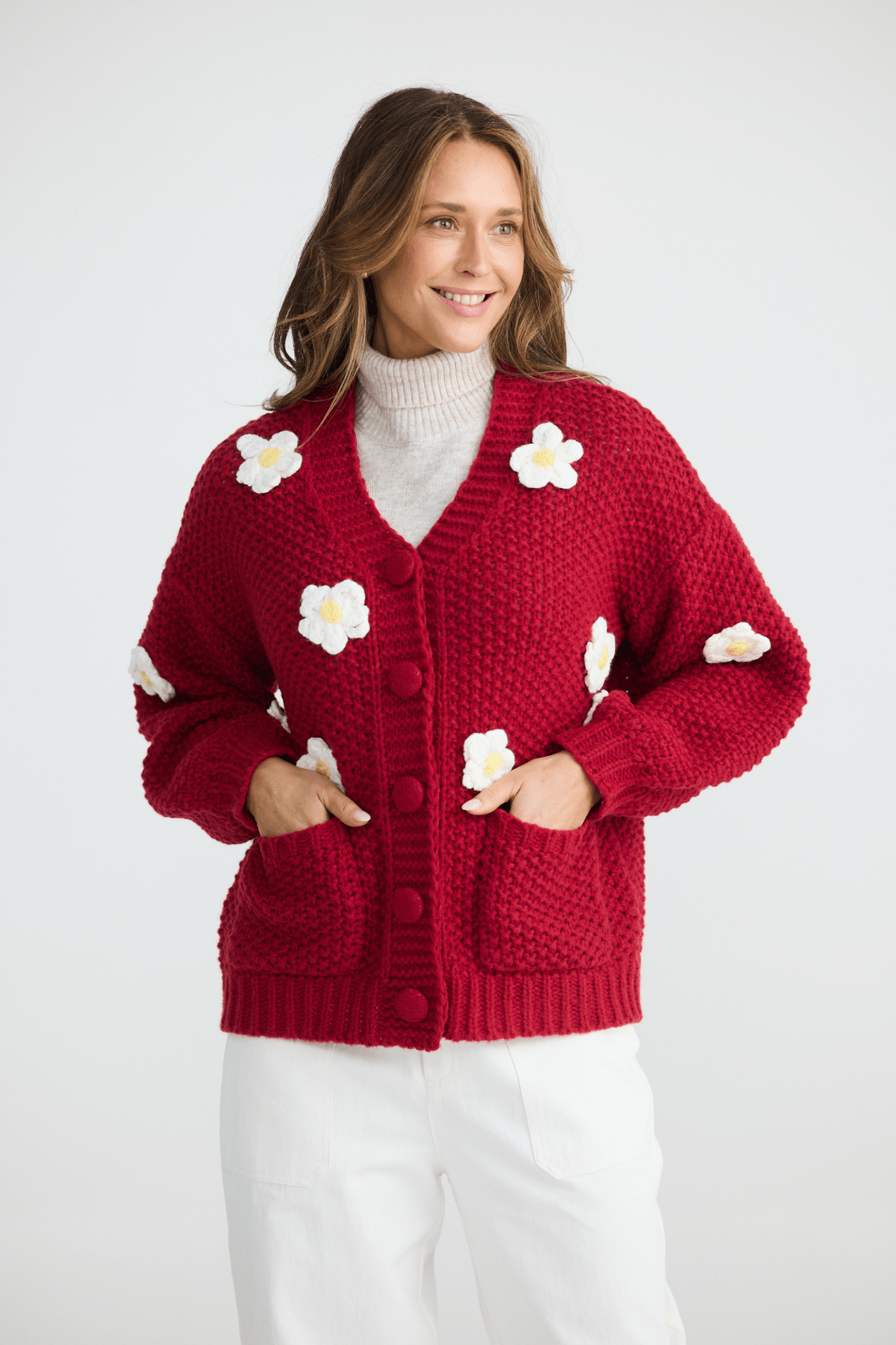 Woman wearing a red cardigan with white flower patterns on a white background