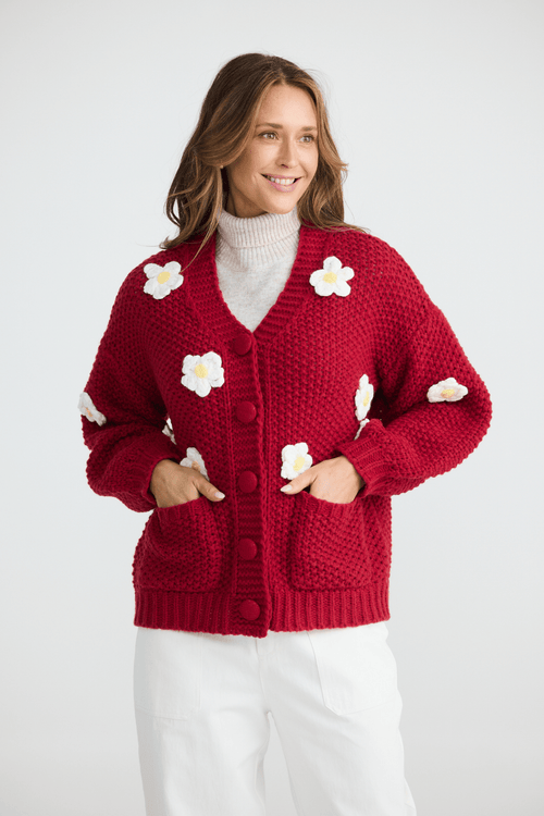 Woman wearing a red cardigan with white flower patterns on a white background
