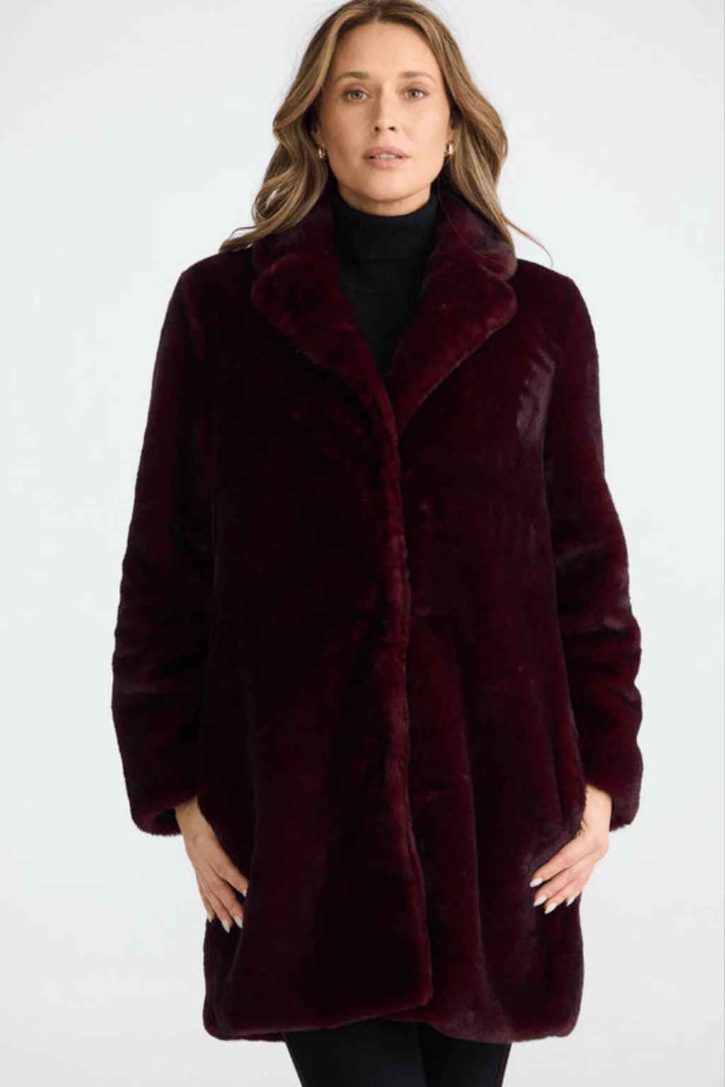 Woman wearing a burgundy faux fur coat on a white background