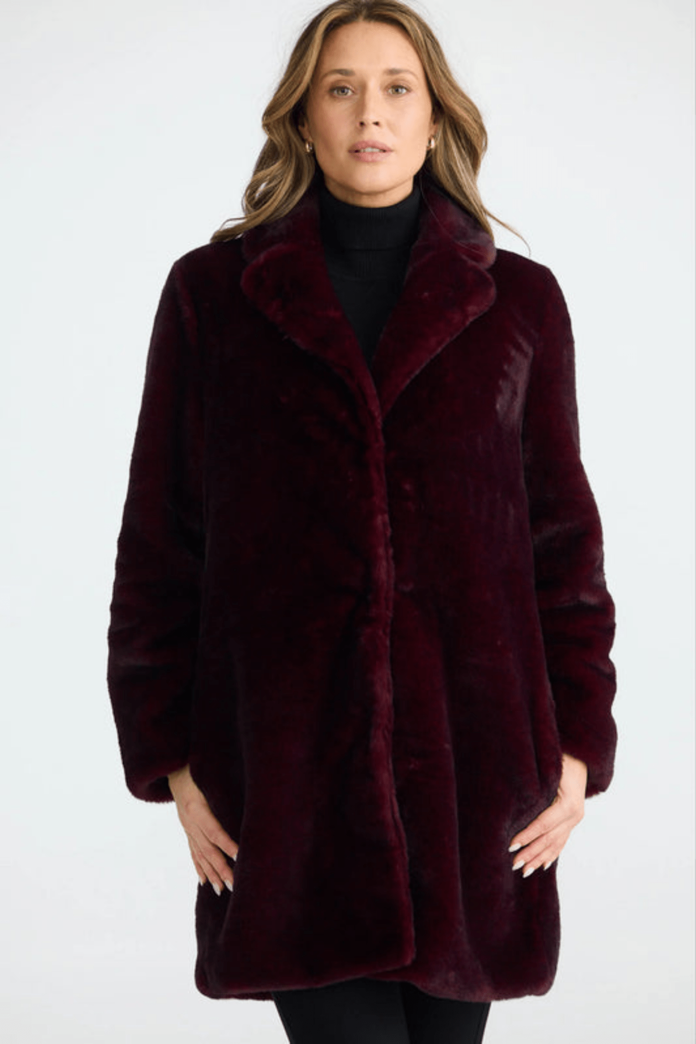 Woman wearing a burgundy faux fur coat on a white background