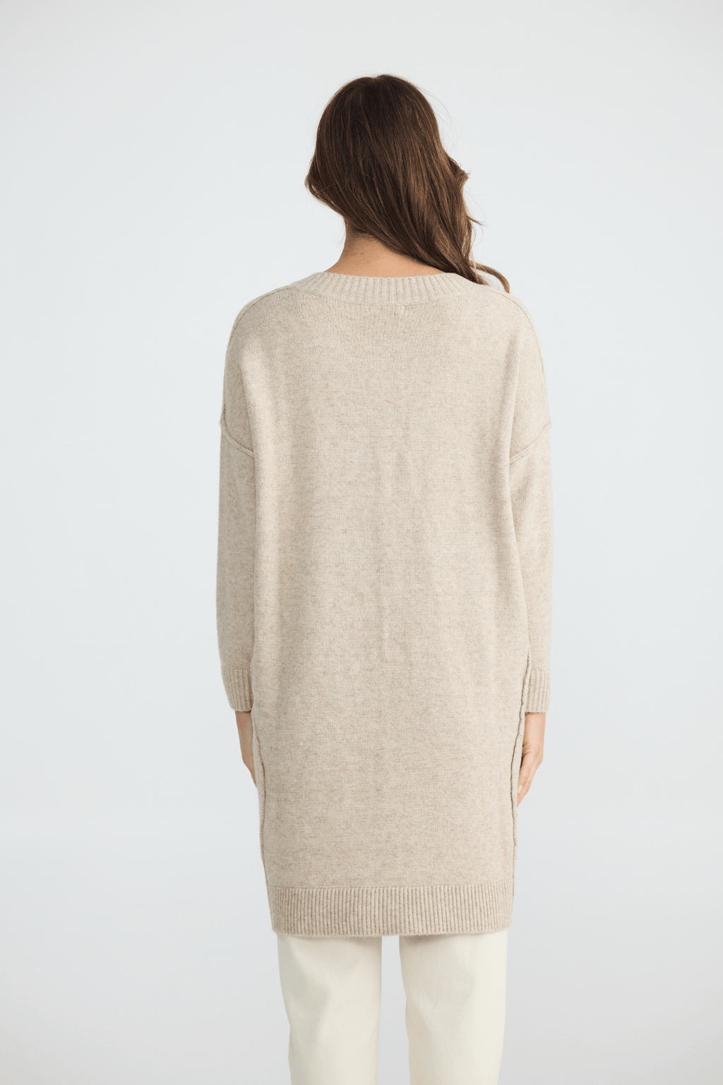 Person wearing a beige sweater on a white background