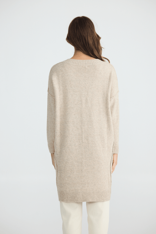Person wearing a beige sweater on a white background