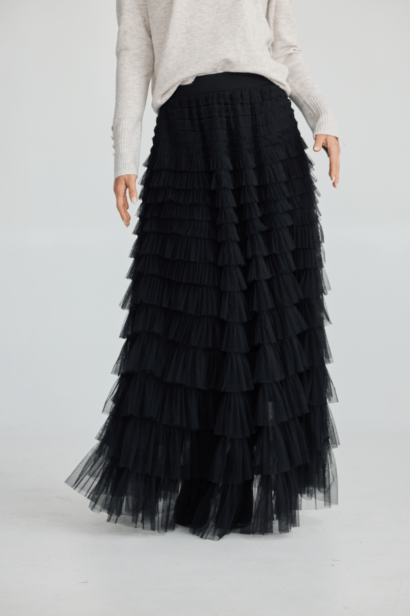 Black tiered skirt worn by a person on a white background
