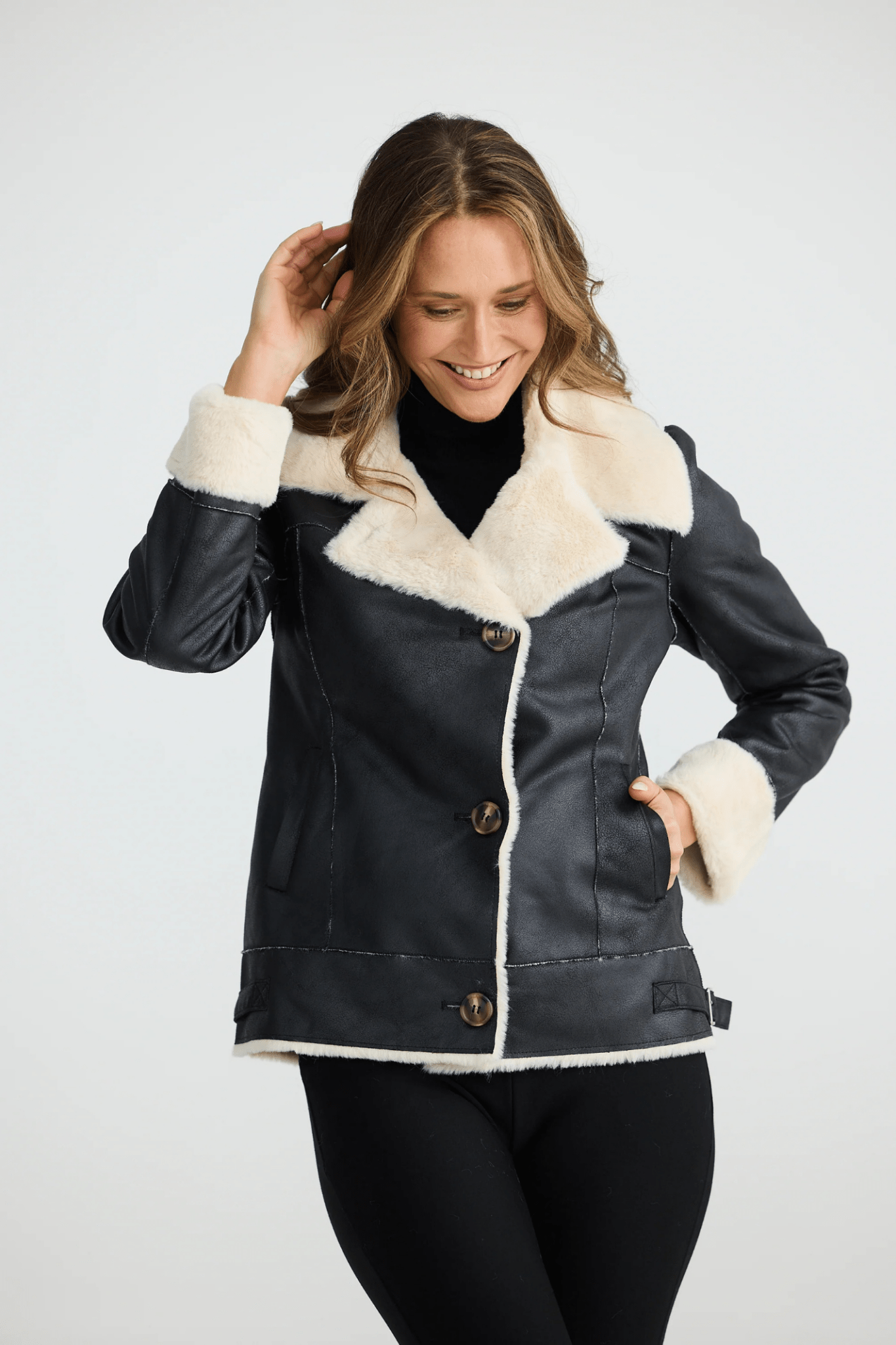 Woman wearing a black coat with white fur trim on a white background. Brave + True BT25161 Haywood Jacket – Black. Shop now at Dotique
