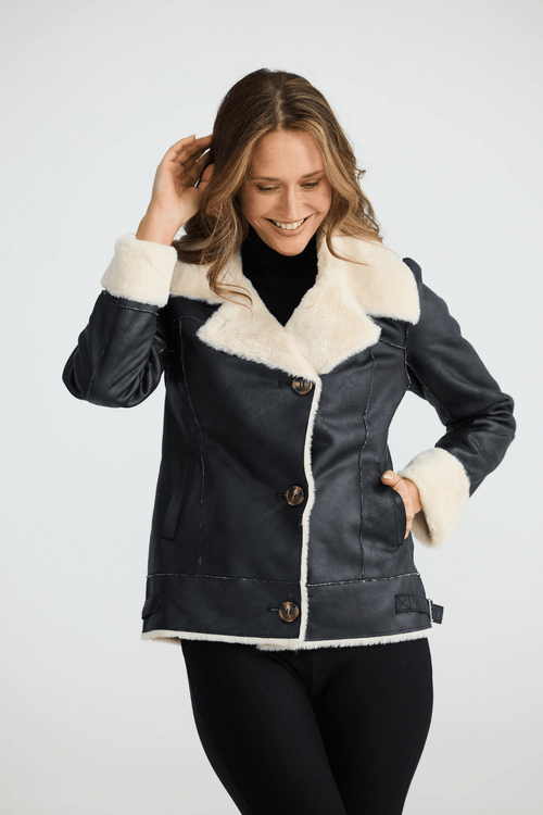 Woman wearing a black coat with white fur trim on a white background. Brave + True BT25161 Haywood Jacket – Black. Shop now at Dotique