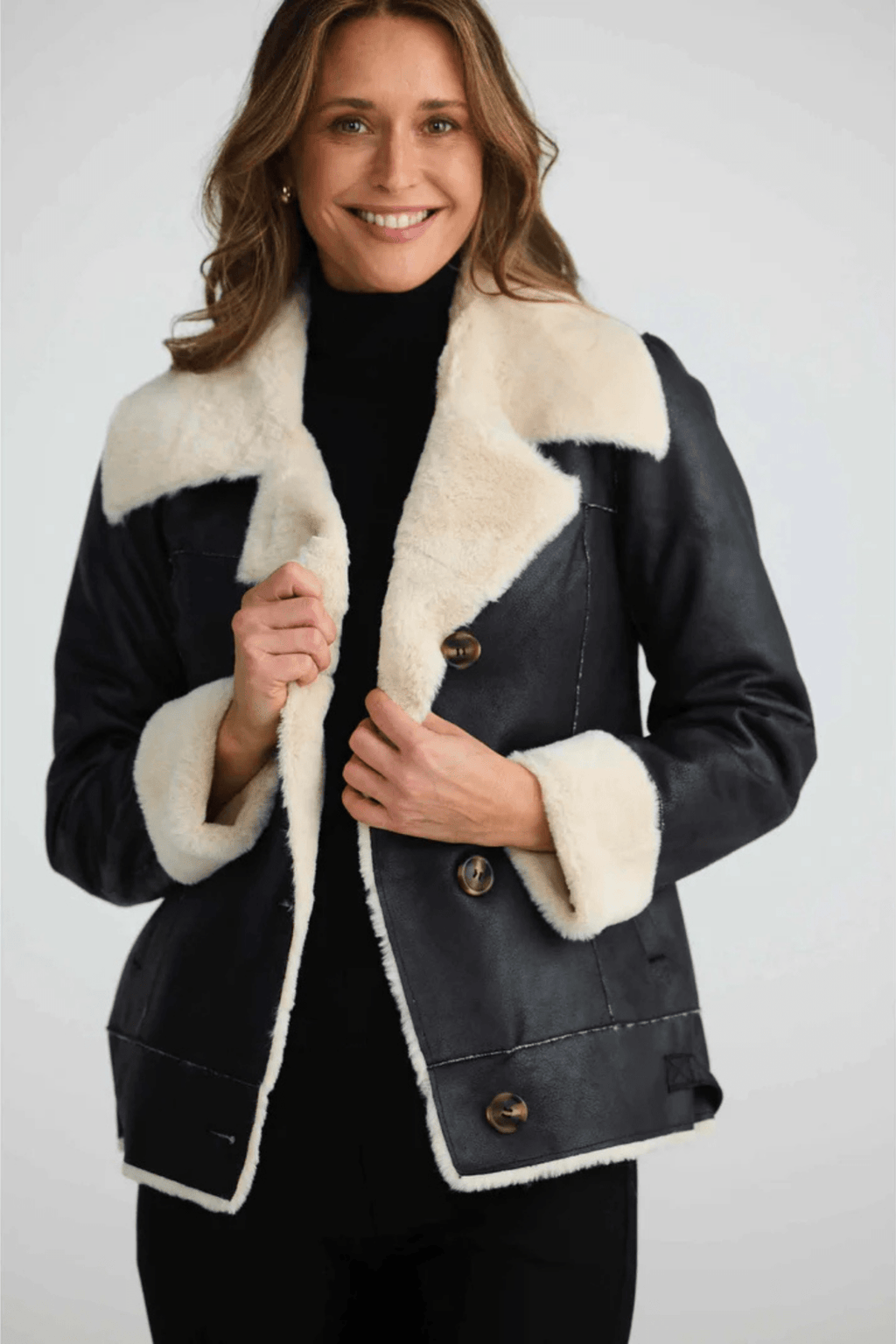 Woman wearing a black coat with white fur trim on a white background. Brave + True BT25161 Haywood Jacket – Black. Shop now at Dotique