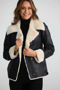 Woman wearing a black coat with white fur trim on a white background. Brave + True BT25161 Haywood Jacket – Black. Shop now at Dotique