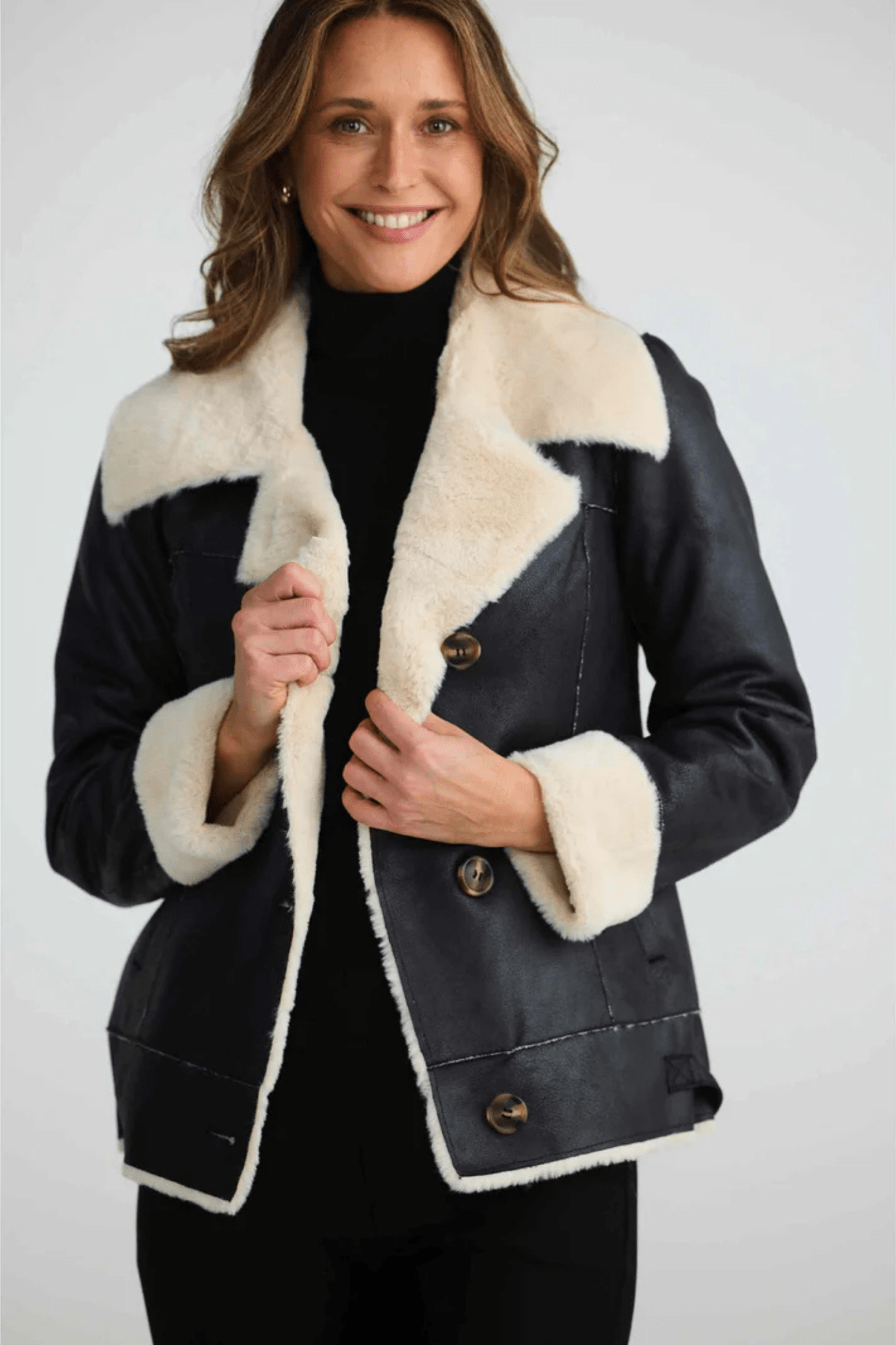 Woman wearing a black coat with white fur trim on a white background. Brave + True BT25161 Haywood Jacket – Black. Shop now at Dotique