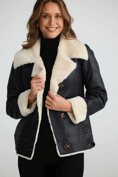 Woman wearing a black coat with white fur trim on a white background. Brave + True BT25161 Haywood Jacket – Black. Shop now at Dotique