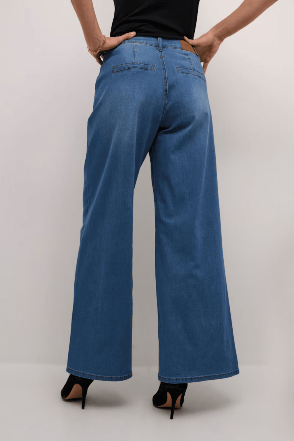 Person wearing blue wide-leg jeans on a plain background