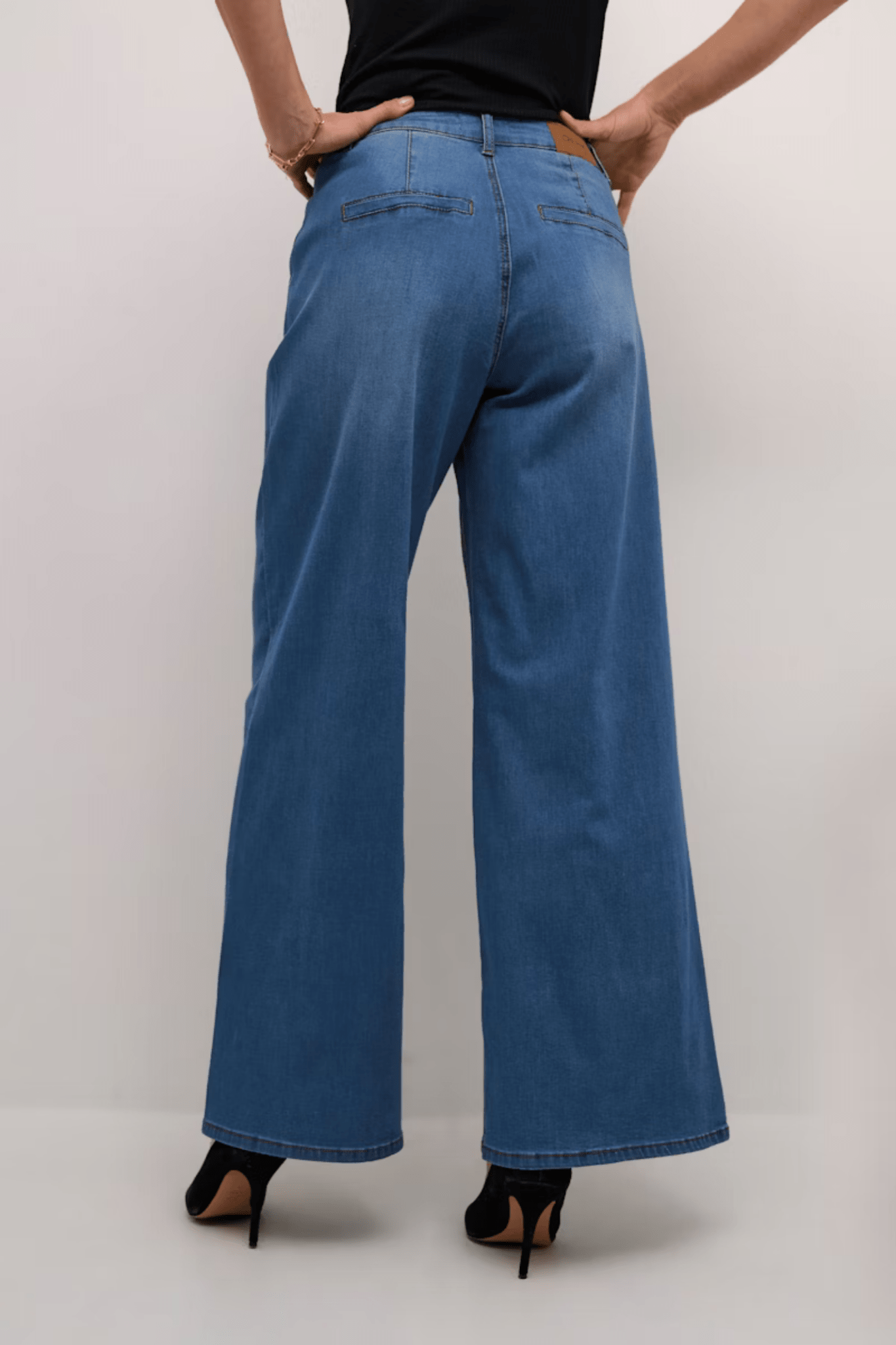 Person wearing blue wide-leg jeans on a plain background
