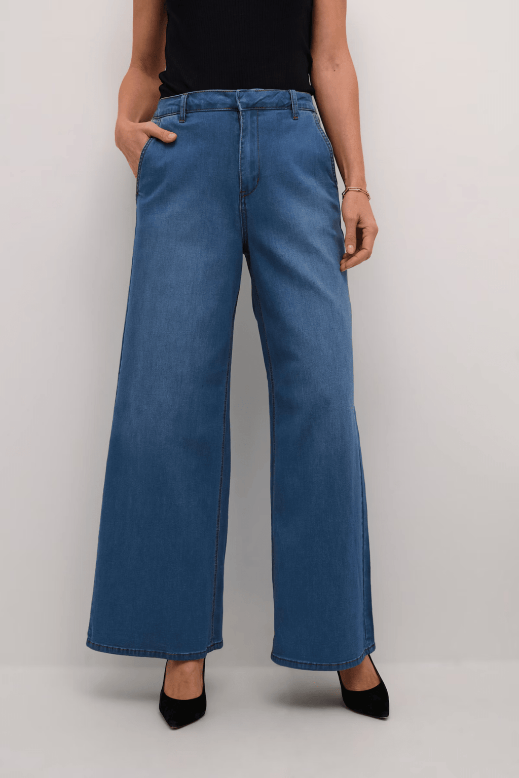 Person wearing blue wide-leg jeans on a plain background