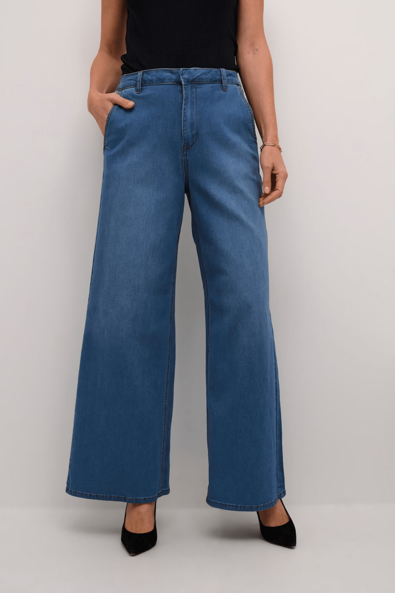 Person wearing blue wide-leg jeans on a plain background