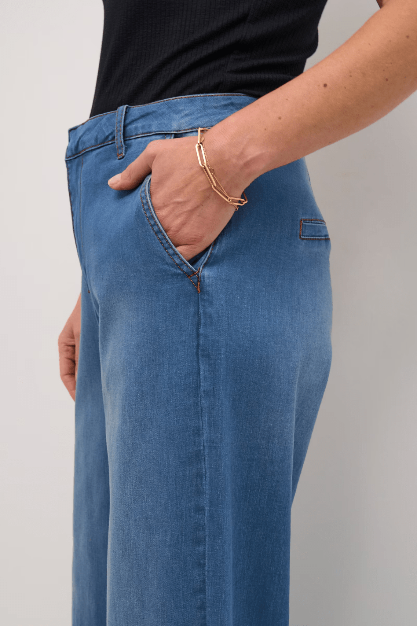 Person wearing blue jeans with a plain background