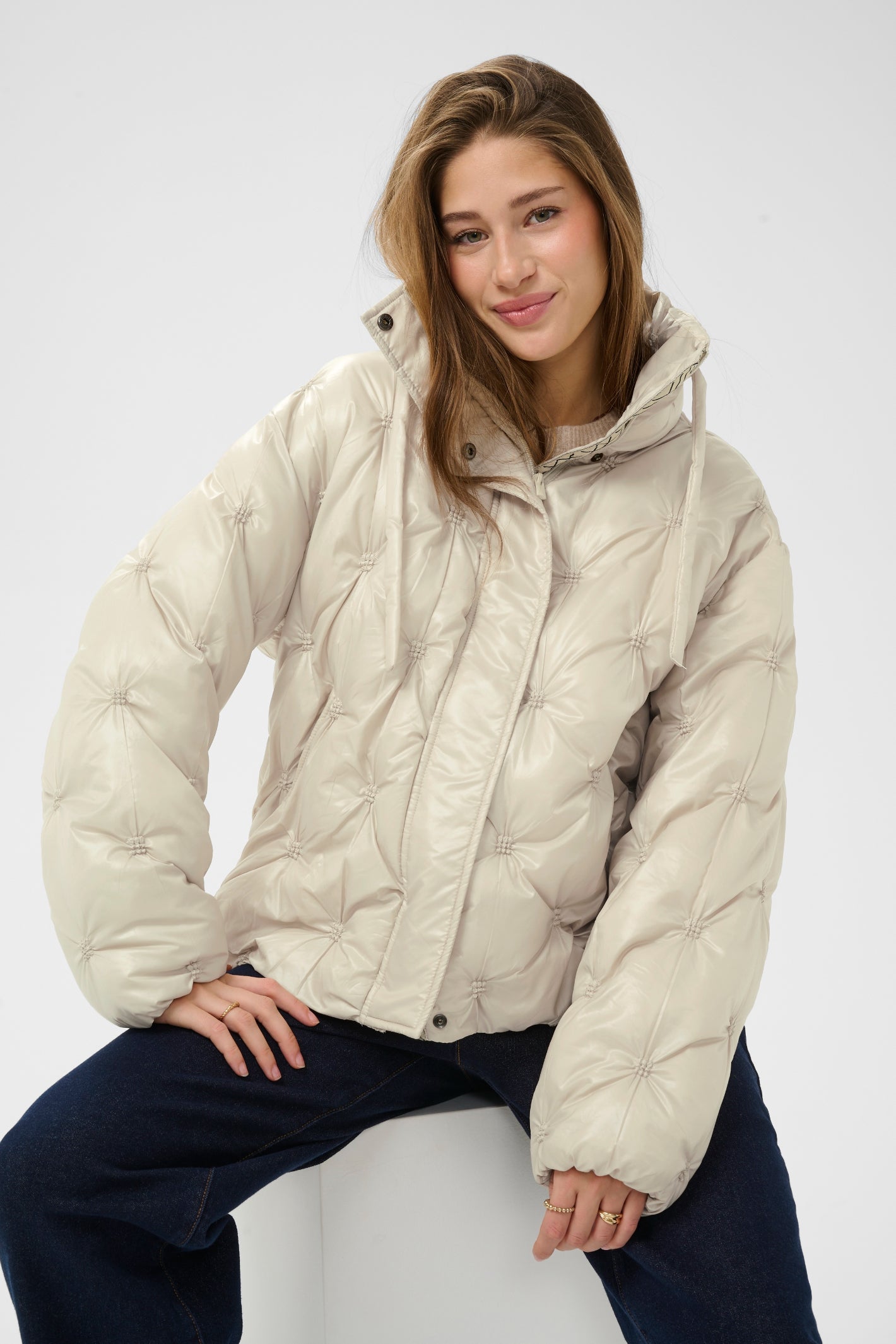 Cream CRDrakie quilted short jacket in Oatmeal featuring a gathered quilted design, hood, high collar and zip fastening.