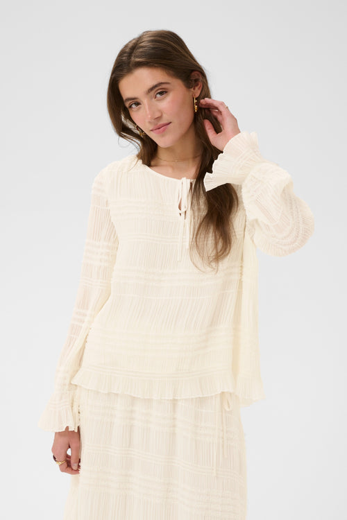 Cream CRSissel textured blouse in Whisper White with tie neckline, layered frill detailing and long ruffle sleeves.