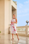 Woman wearing Dolcezza 26685 White Pink Floral Linen Dress by Dolcezza styled with a matching scarf, posing on a terrace. Shop Dolcezza at Dotique.