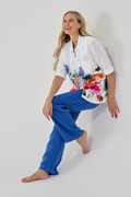 Smiling model wearing Dolcezza Floral Print Linen Shirt 26702 with colorful floral design on white fabric and blue linen pants by Dolcezza, shop Dolcezza at Dotique.