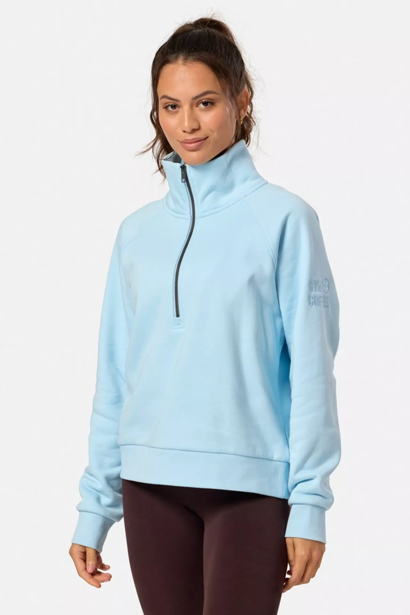 Woman wearing Gym+Coffee Clubhouse Quarter Zip in Baby Blue by Gym+Coffee, shop the Gym+Coffee range at Dotique.