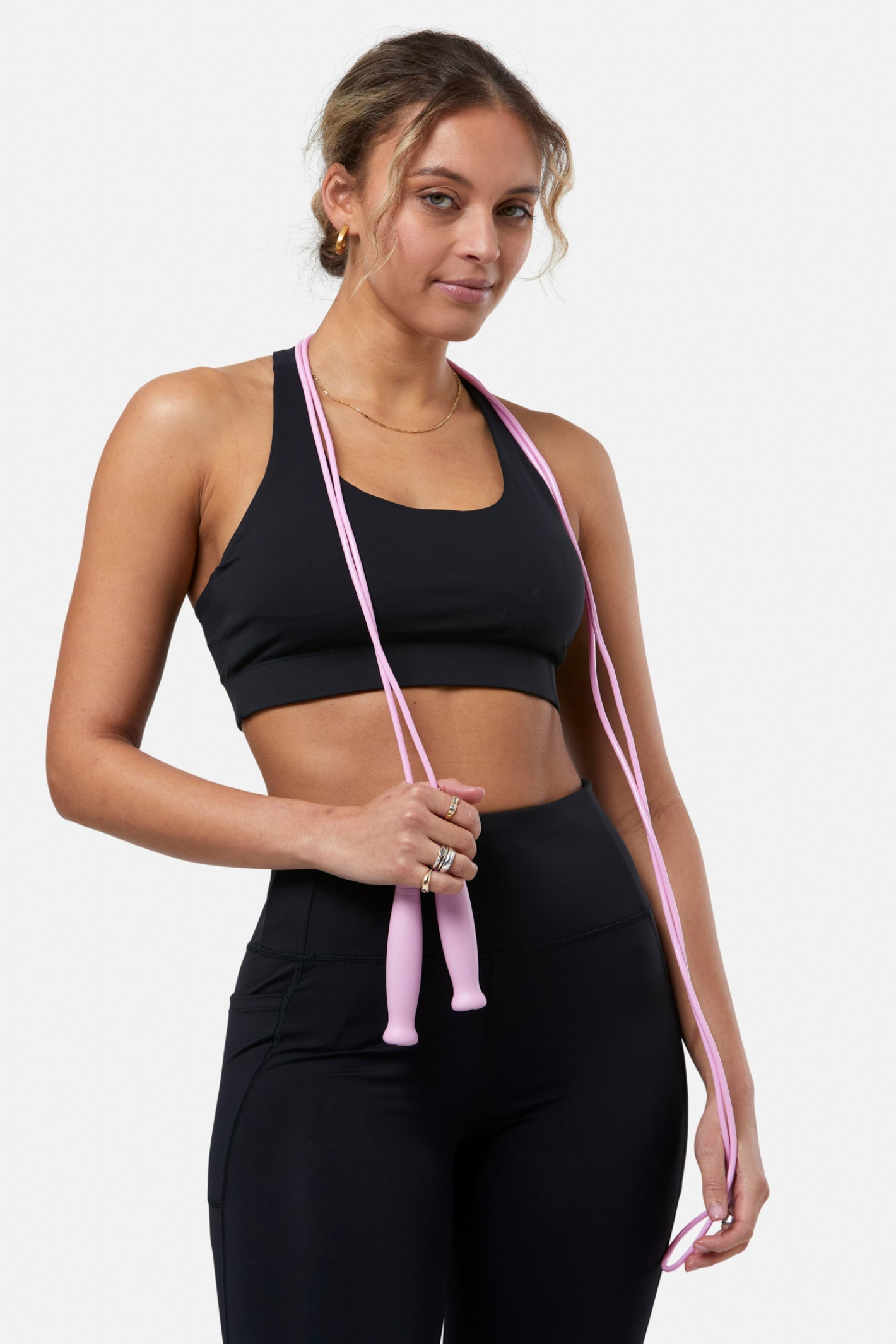 Model wearing Gym+Coffee Relentless Bra Black by Gym+Coffee holding a pink jump rope, shop Gym+Coffee at Dotique.
