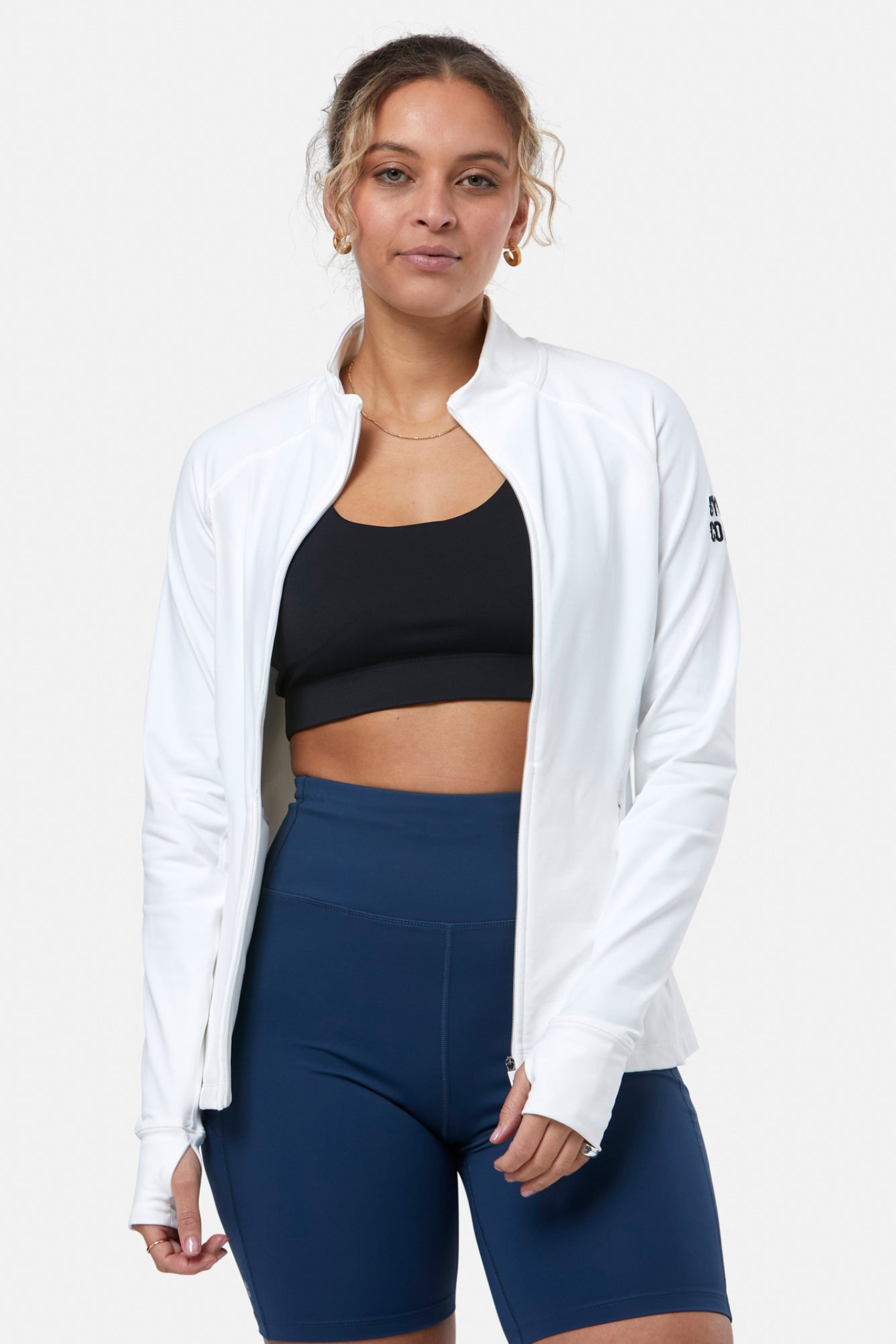 Woman wearing Gym+Coffee Relentless Full Zip Jacket in Ultra White by Gym+Coffee, shop the Gym+Coffee collection at Dotique