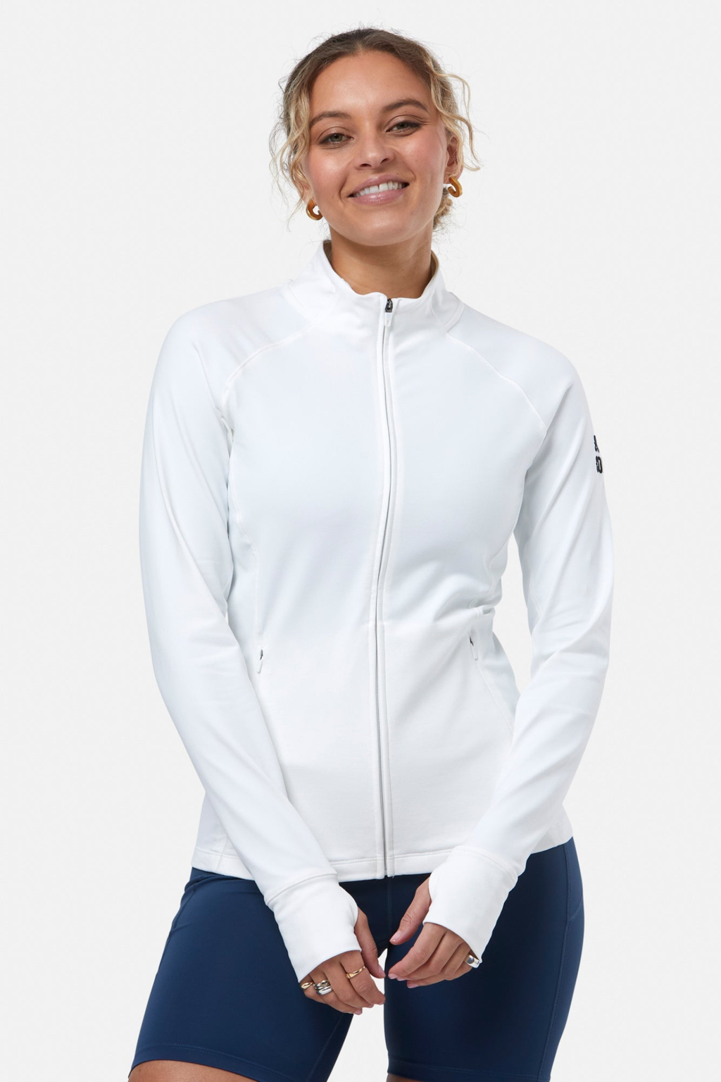 Smiling woman wearing Gym+Coffee Relentless Full Zip Jacket in Ultra White by Gym+Coffee, shop Gym+Coffee at Dotique.